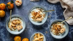 three bowls filled with oatmeal next to oranges