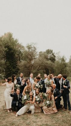 a group of people standing next to each other in front of some trees and grass