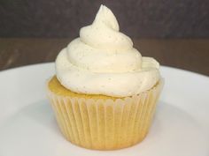 a cupcake with white frosting sitting on a plate