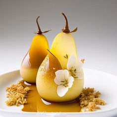 two pears are sitting on a plate with caramel sauce and flowers in them