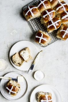 hot cross buns with icing on white plates next to utensils and spoon