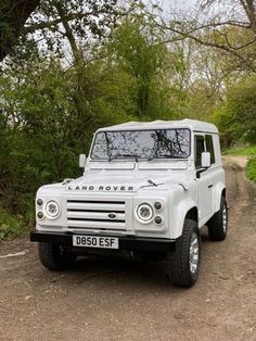 a white land rover is parked on a dirt road