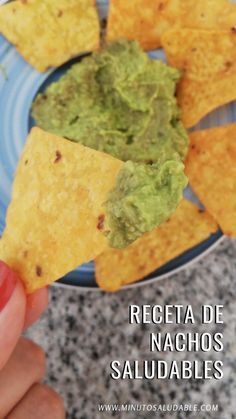 a hand holding a tortilla chip with guacamole