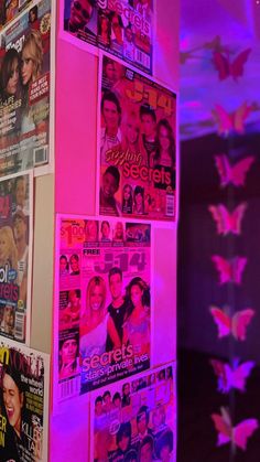 the wall is covered with many different magazine covers and pink lighting in front of it