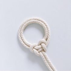 a white rope is tied up on a white surface with a knot at the end