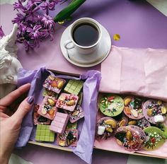 a person is holding a tray with pastries in it next to a cup of coffee