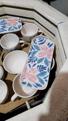 there are many bowls and spoons in the bowl on the counter top, all decorated with blue and pink flowers