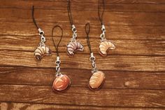 four seashells are hanging from silver earwires on a wooden surface,