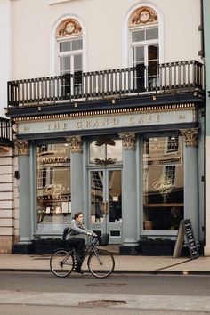 a man riding a bike past a store front