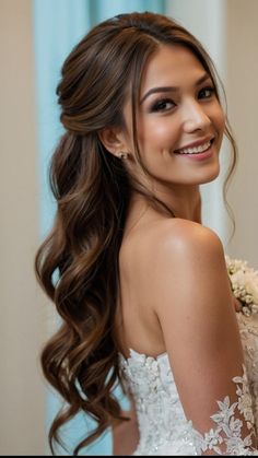 a woman with long hair wearing a wedding dress and holding flowers in her hand, smiling at the camera