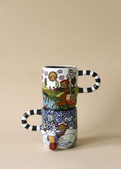 three coffee mugs are stacked on top of each other with designs painted on them