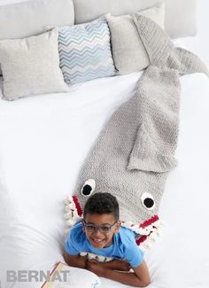 a young boy laying on top of a bed next to a book and stuffed animal