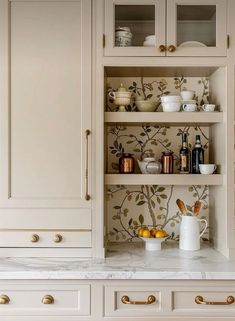 a kitchen with white cabinets and marble counter tops, gold pulls on the doors and brass knobs