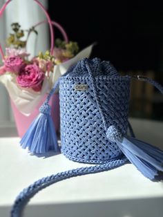 a blue purse sitting on top of a table next to a pink flower vase with flowers in it