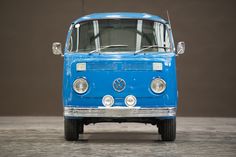 an old blue van parked on top of a cement floor next to a wall and window