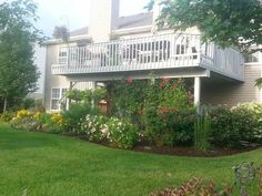 a house with flowers in the front yard and landscaping on the side walk to the second story