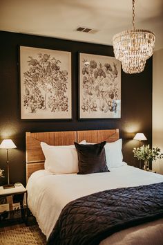 a bedroom with two pictures on the wall above the bed and lamps hanging from the ceiling