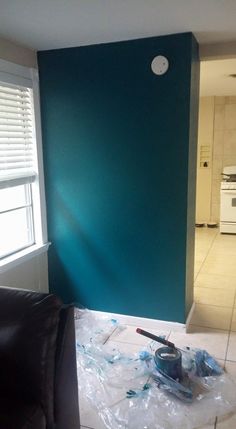 a living room with blue walls and tile flooring in the process of being painted