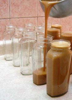 a person pouring caramel into jars on a counter