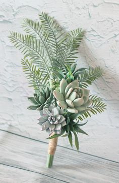 a bouquet of succulents and ferns on a wooden table with white background