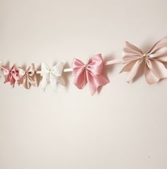 three pink and white bows are hanging on the wall