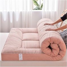 a woman sitting on top of a pink checkered couch next to a white table