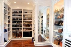 an empty walk in closet with many shoes on the shelves and purses on the floor