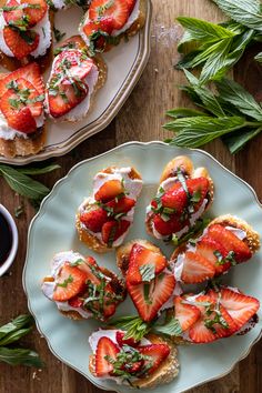 strawberries are arranged on top of toasted bread and garnished with fresh herbs