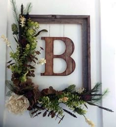 the letter b is surrounded by flowers and greenery in front of a wooden frame