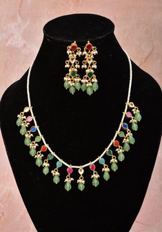 When you are looking for jewelry that instantly makes a statement and at the same time is versatile and simple enough to wear on many occasions then this dainty and lightweight piece has what you are looking for. One row of white beads holds evenly spaced Multicolor Kundan entrusted small pendants. The units are micro-plated in gold to give it a gold jewelry-like finish. The set comes with adjustable closure and a matching pair of earrings. One can effortlessly pair with many ensembles to create Dainty Dangling Beads Jewelry For Party, Fusion Style Multicolor Teardrop Jewelry, Multicolor Teardrop Fusion Jewelry, Green Jewelry Sets With Dangling Beads For Gift, Delicate Dangling Beads Jewelry For Parties, Elegant Green Jewelry Sets With Dangling Beads, Dainty Green Jewelry With Colorful Beads, Festive White Jewelry With Colorful Beads, Multicolor Kundan Necklace With Dangling Beads For Wedding