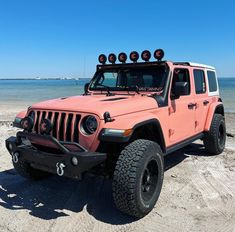 a pink jeep parked on top of a sandy beach