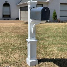 a white mailbox in front of a house on the side of a field with grass