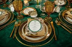 the table is set with gold and green plates, silverware, and napkins