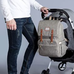 a man standing next to a stroller with a backpack on it's back