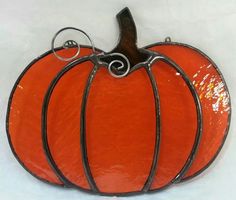 an orange glass pumpkin sitting on top of a white table next to a black wire