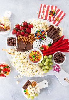 a platter filled with popcorn, chocolates, strawberries, and candy bars