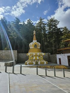 a large yellow and white statue sitting in the middle of a park next to trees