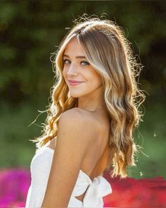 a woman with blonde hair wearing a white dress and looking at the camera, smiling