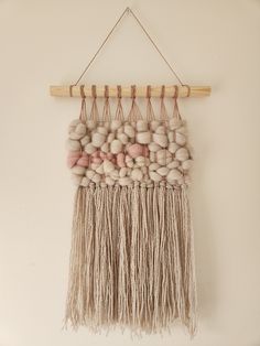 a wall hanging made out of balls and yarn with a wooden stick attached to it