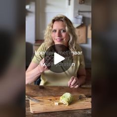 a woman is cutting up an artichoke on a wooden board