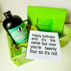 a birthday card sitting on top of a basket next to a bottle of alcohol and a note