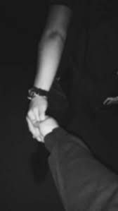 black and white photograph of two people holding each other's hands in the dark