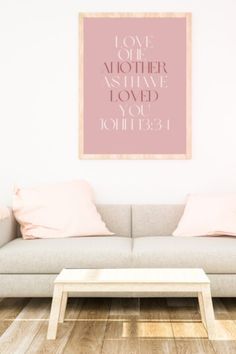 a living room with a couch, coffee table and pink wall art on the wall