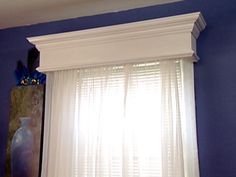 an empty room with blue walls and white drapes on the windowsill, in front of a large vase