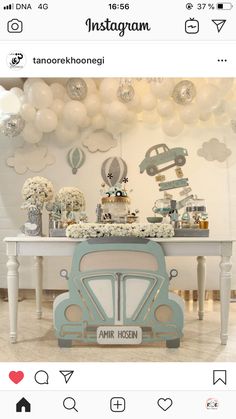 a table with balloons and an old car on it in front of a white wall