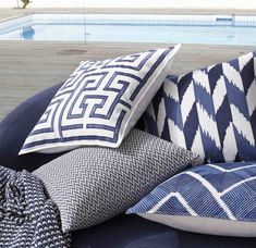 blue and white pillows sitting on top of a couch next to a swimming pool