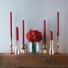 red flowers and candles are arranged on a mantle