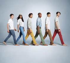 a group of men and women walking down the street in different colored pants, shirts and hats