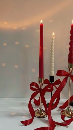 two candles with red ribbon on them sitting next to each other