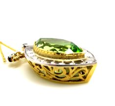 This beautiful, statement features an unusual, marquise shape peridot in a necklace that will never go out of style. The peridot is far less yellowish-green than most peridot; rather, it is a slightly "minty" green color. It is set in a yellow gold bezel and framed with a striking white gold border. Accented by four small, round white cut diamonds in the elaborately designed bail, this is a one-of-a-kind piece, handmade of 18k yellow and white gold by our Master Jewelers in Los Angeles. The leve Elegant Yellow Marquise Jewelry, Yellow Marquise Fine Jewelry, Elegant Yellow Marquise Cut Jewelry, Oval Green Peridot Necklaces, Formal Green Marquise Jewelry, Fine Jewelry Green Marquise Necklaces, Green Marquise Cut Jewelry For Gifts, Elegant Green Marquise Necklace, Green Marquise Hallmarked Jewelry